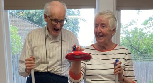 Photograph of elderly man and women stood together playing version of hockey