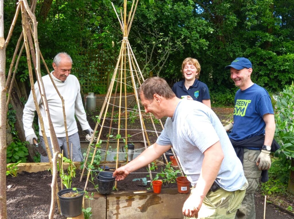 Photograph of four people gardening and smiling