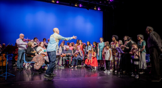 Mixed group of adults and children playing musical instruments and singing