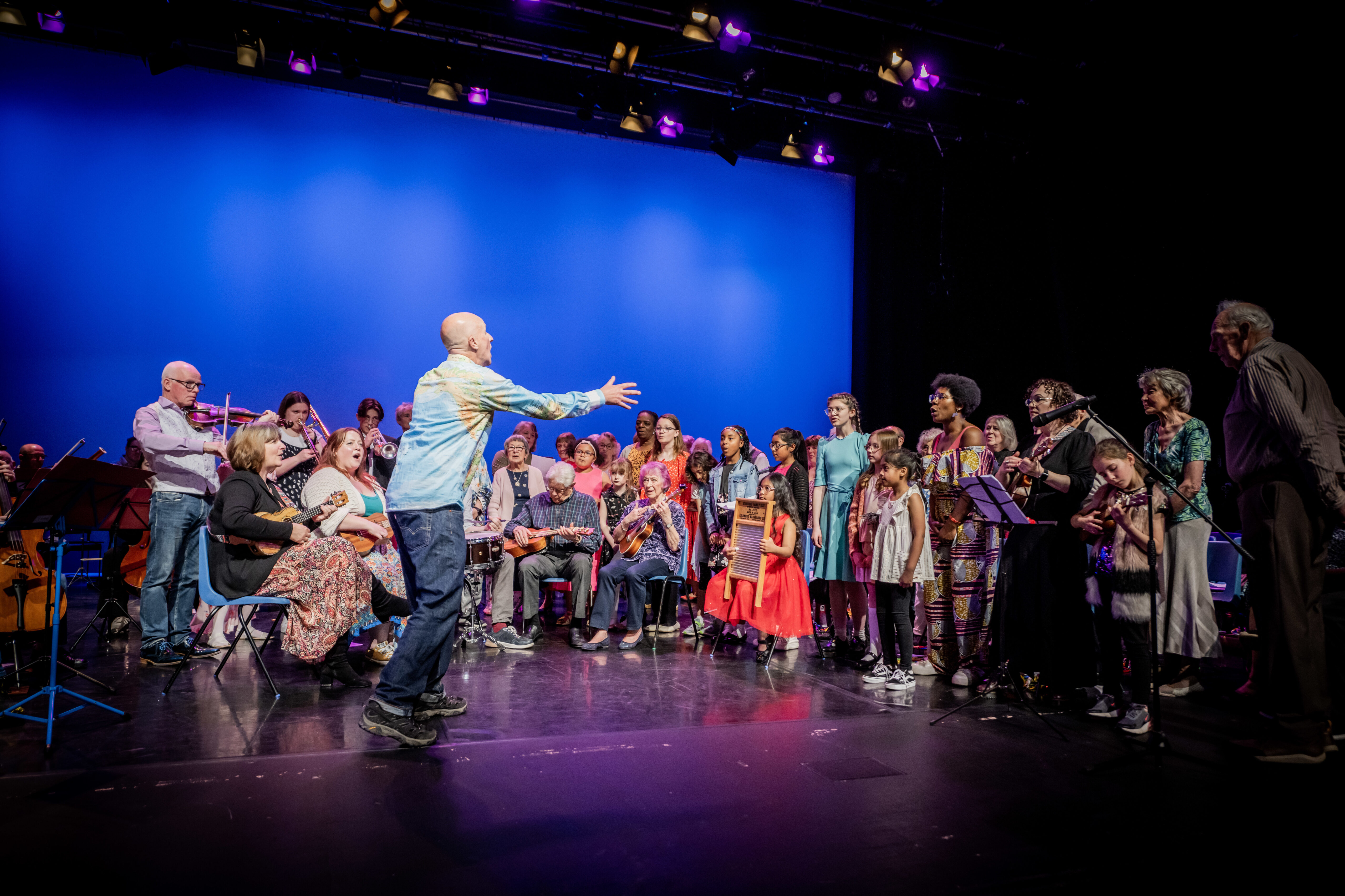 Mixed group of adults and children playing musical instruments and singing