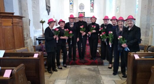 Group of nine women in village church holding flowers